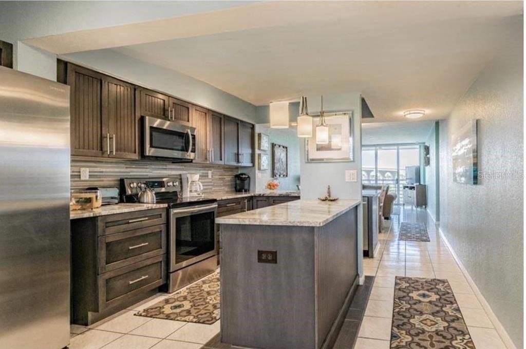 A kitchen with dark wood cabinets, stainless steel appliances, and a stone-topped island — 5901 BAHIA DEL MAR CIRCLE UNIT 422, ST PETERSBURG, FL