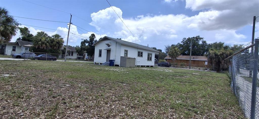 A white, single-story house sits on a grassy lot with a chain-link fence nearby — 3009 N 13TH STREET, TAMPA, FL