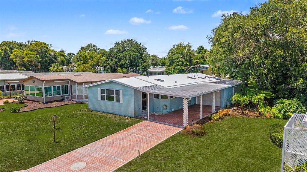 An exterior view of a light blue single-story home with a brick driveway and carport — 316 PORTSIDE LANE, EDGEWATER, FL