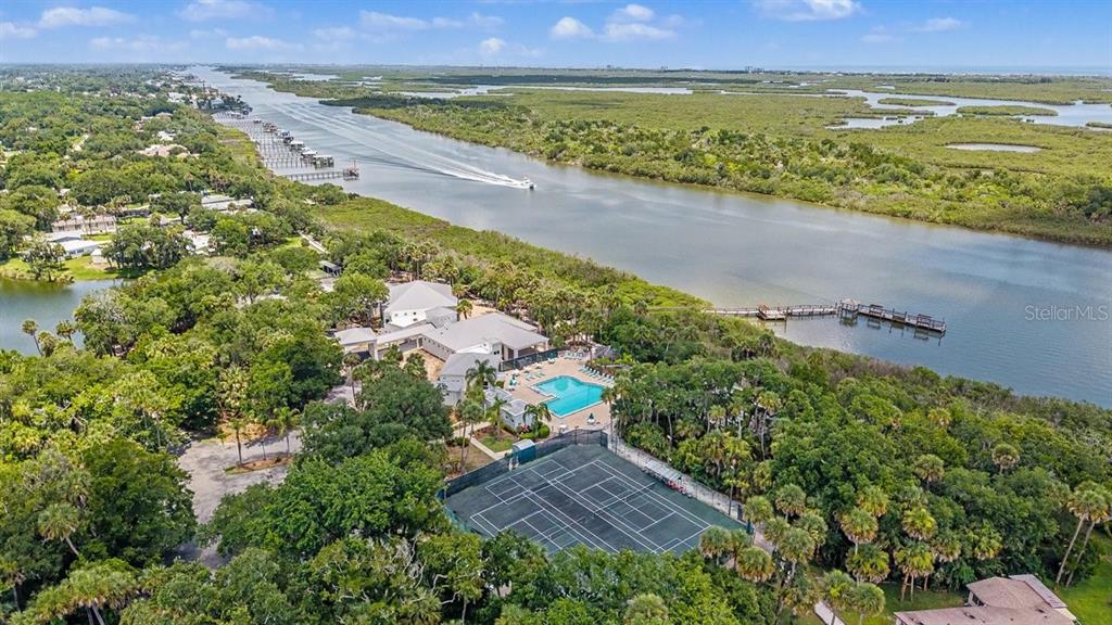 An aerial view shows a house with a pool and tennis court near a river — 316 PORTSIDE LANE, EDGEWATER, FL