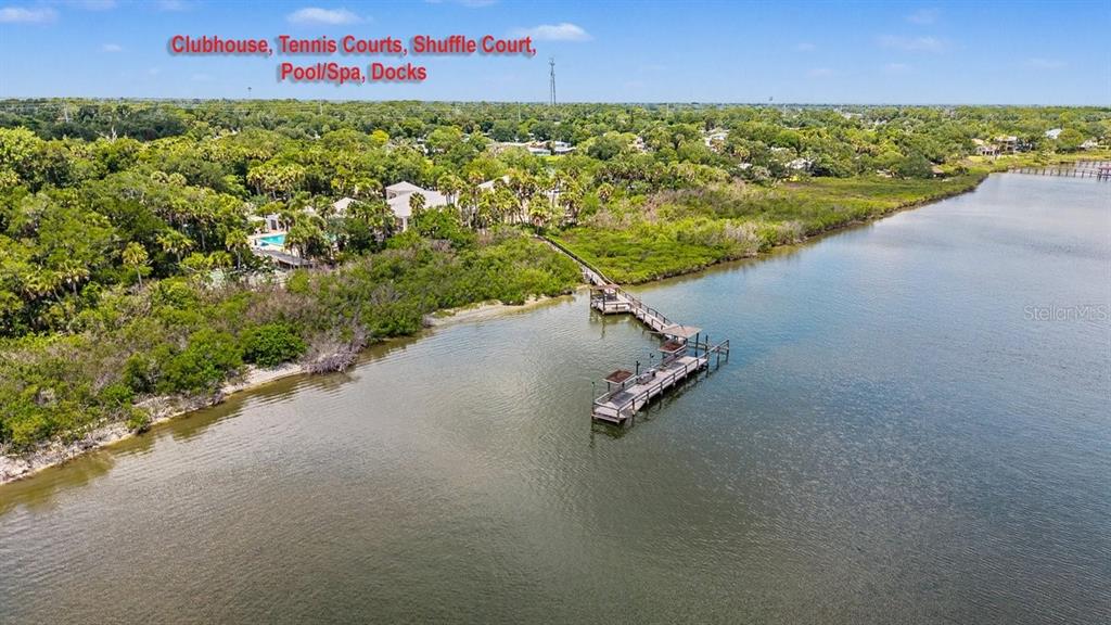 An aerial view shows a wooden dock extending into a river near a community clubhouse — 316 PORTSIDE LANE, EDGEWATER, FL