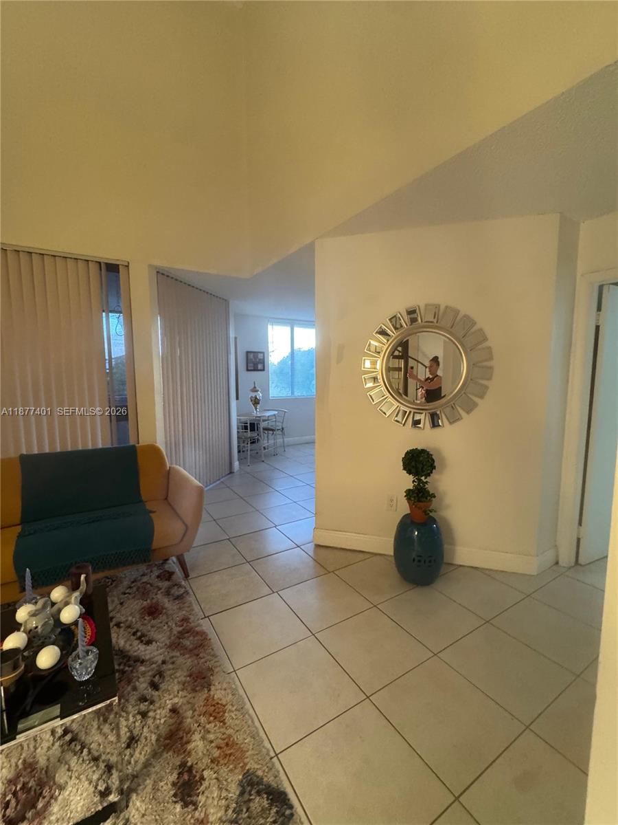 A living area with tile floors, a yellow sofa, and a decorative mirror on the wall — 8205 SW 152nd Ave # 414, Miami FL 33193, MIAMI, FL
