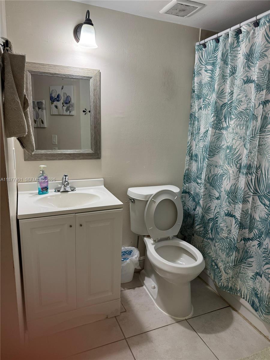 A bathroom features a white vanity, a toilet, and a shower with a patterned curtain — 8205 SW 152nd Ave # 414, Miami FL 33193, MIAMI, FL