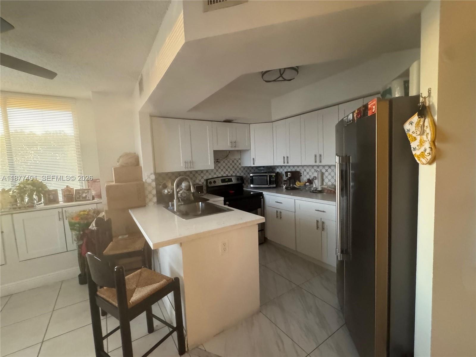 A kitchen features white cabinets, a peninsula with a sink, and stainless steel appliances — 8205 SW 152nd Ave # 414, Miami FL 33193, MIAMI, FL
