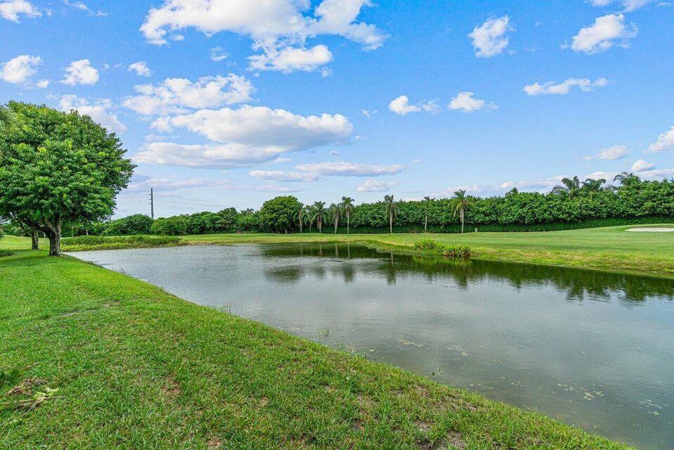 A pond sits in the foreground of a grassy golf course with trees in the background — 6446 Aspen Glen Circle, Boynton Beach FL 33437, BOYNTON BEACH, FL