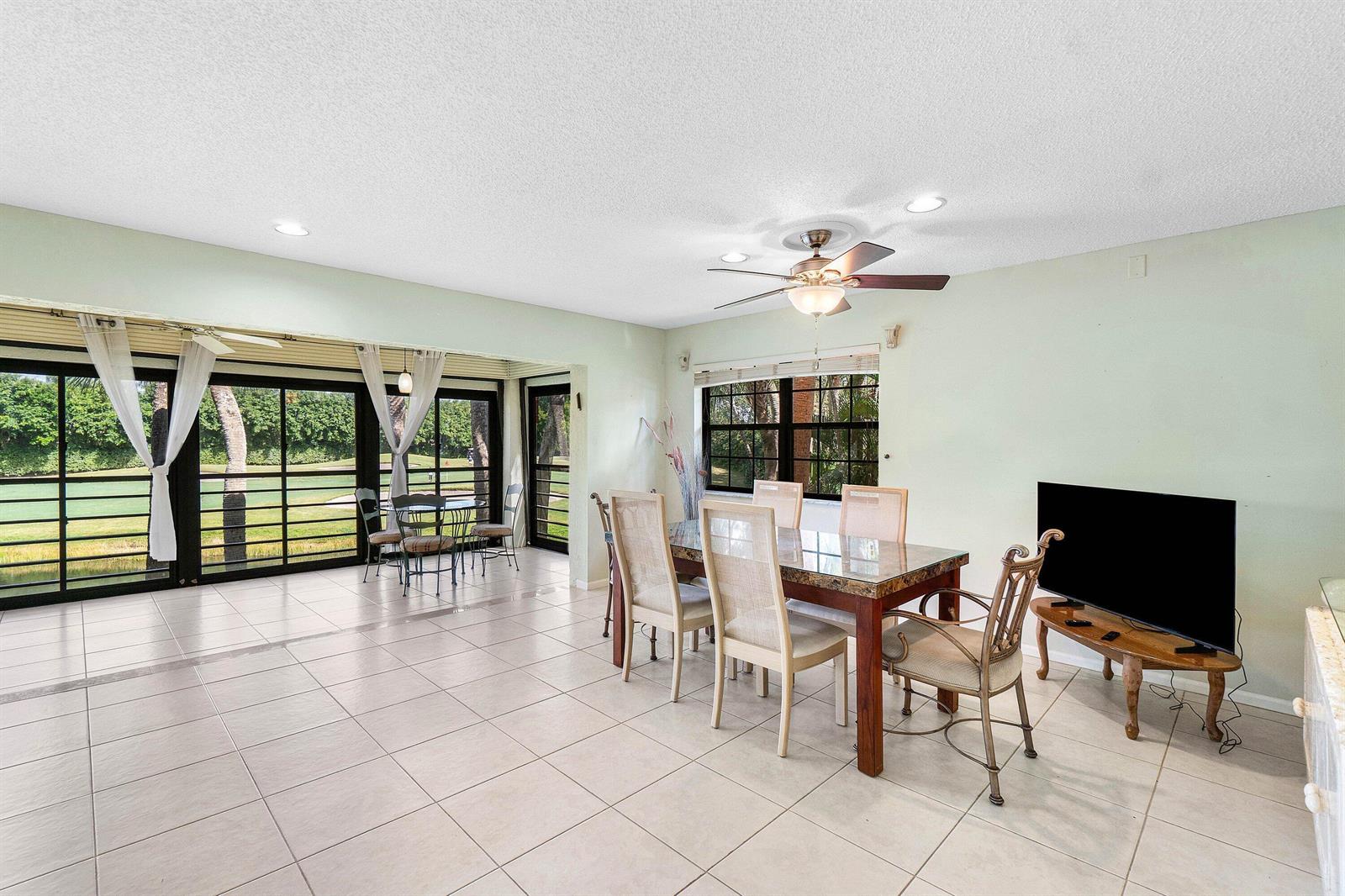 A dining room with tile floors, a glass-topped table, and a view of a golf course — 6446 Aspen Glen Circle, Boynton Beach FL 33437, BOYNTON BEACH, FL