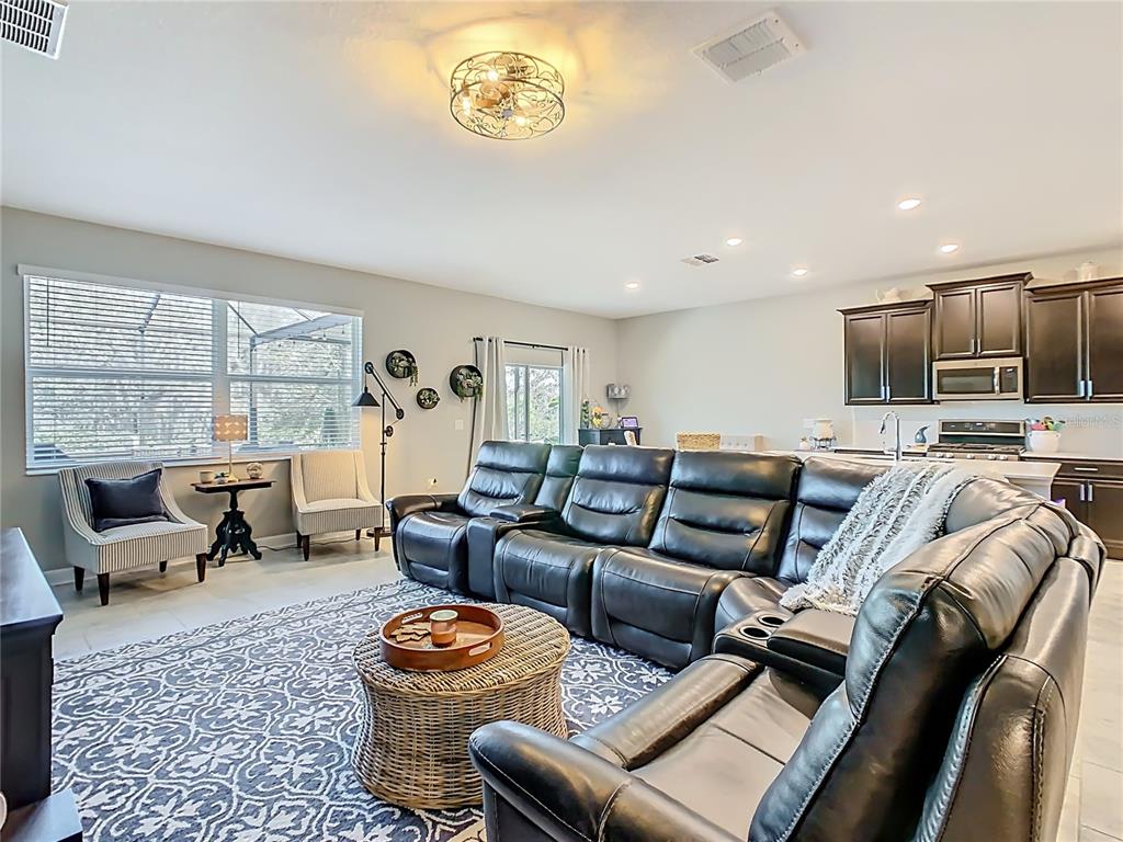 A living room features a large black sectional sofa, a wicker coffee table, and an open kitchen — 1055 OAK BLUFF DRIVE, DAVENPORT, FL