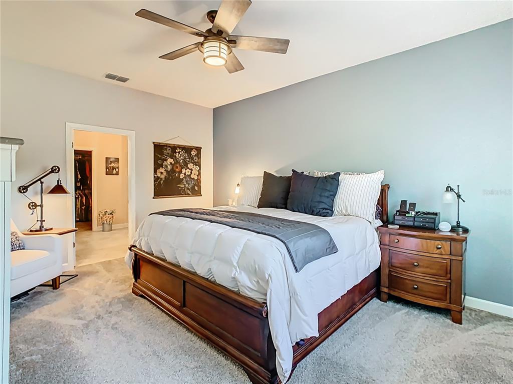 A bedroom features a wooden bed frame, a blue accent wall, and a ceiling fan — 1055 OAK BLUFF DRIVE, DAVENPORT, FL