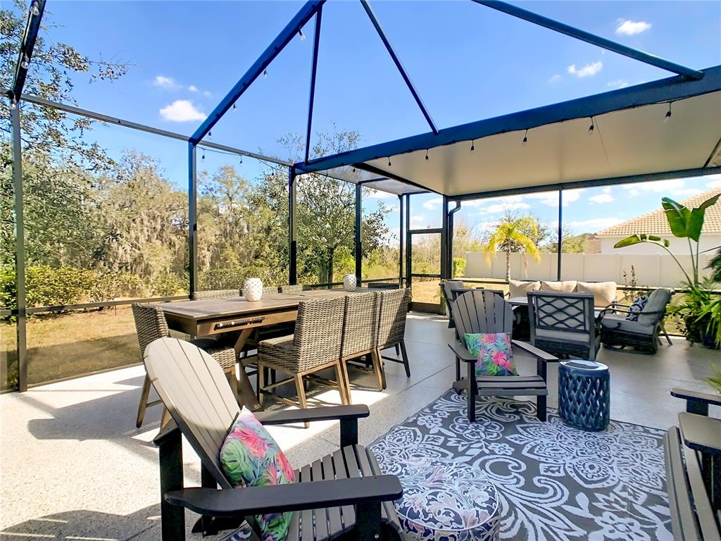 A screened-in patio features a dining set, lounge chairs, and a patterned rug — 1055 OAK BLUFF DRIVE, DAVENPORT, FL