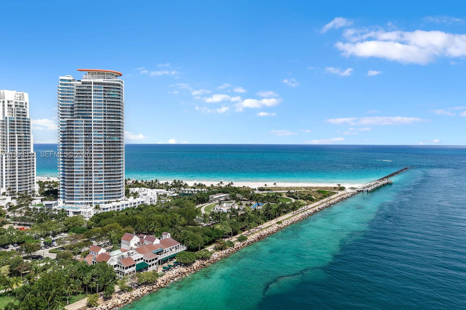 An aerial view shows a coastal park with a jetty, beach, and high-rise buildings — 100 S Pointe Dr, Miami Beach FL 33139, MIAMI BEACH, FL