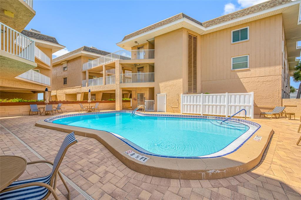 An outdoor swimming pool is surrounded by a paved deck and multi-story apartment buildings — 3100 GULF BOULEVARD UNIT 132, BELLEAIR BEACH, FL