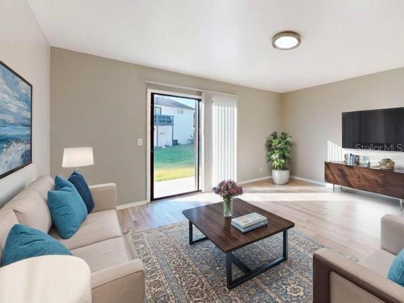 A living room features light wood floors, a sliding glass door, and a television console — 4701 31ST STREET S UNIT B2, ST PETERSBURG, FL
