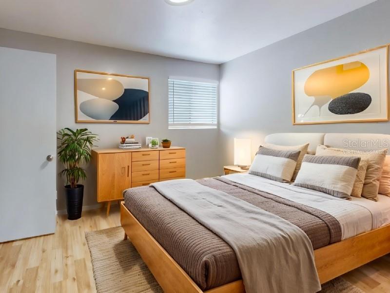 A bedroom features a wooden bed frame, a matching dresser, and two framed abstract prints — 4701 31ST STREET S UNIT B2, ST PETERSBURG, FL