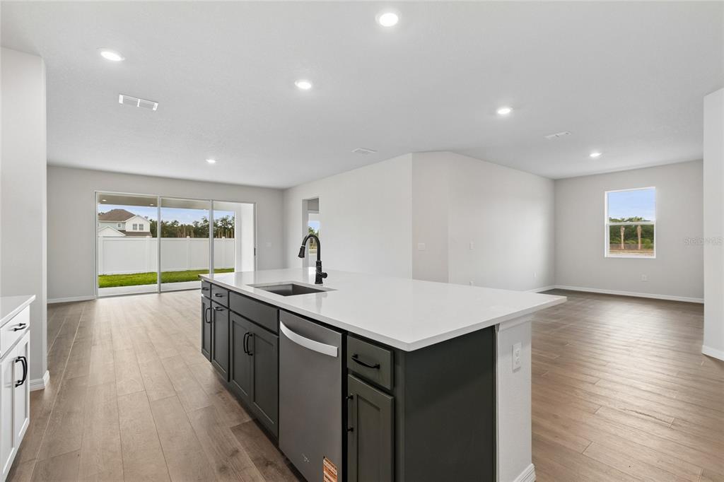 A modern kitchen features white cabinetry, a gray island, stainless steel appliances, and wood flooring — 614 KINGSWOOD COURT, BRADENTON, FL