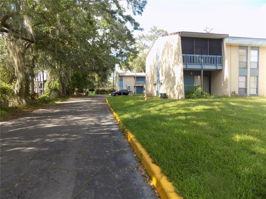 A paved driveway leads toward two-story apartment buildings with balconies and surrounding green space — 2811 SW ARCHER ROAD UNIT x 201, GAINESVILLE, FL