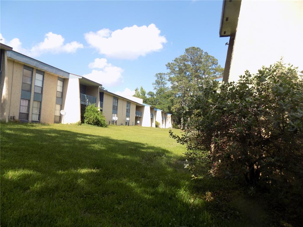 A grassy lawn sits in front of a multi-story apartment building under a blue sky — 2811 SW ARCHER ROAD UNIT x 201, GAINESVILLE, FL