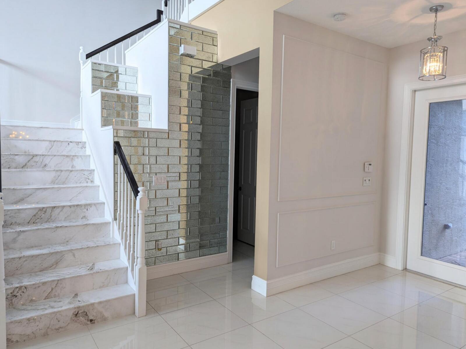 A staircase with marble steps and a mirrored wall next to a paneled entryway wall — 16645 Germaine Drive, Delray Beach FL 33446, DELRAY BEACH, FL