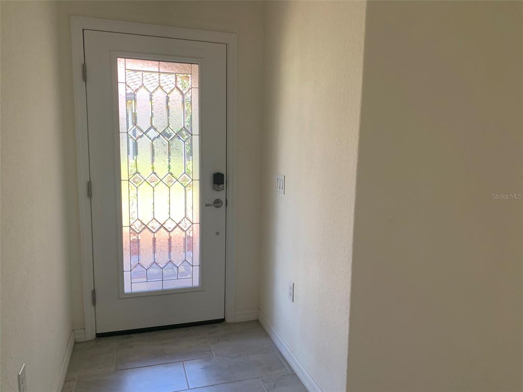 A white front door with a decorative glass insert opens into a tiled entryway — 12259 AMICA LOOP, VENICE, FL