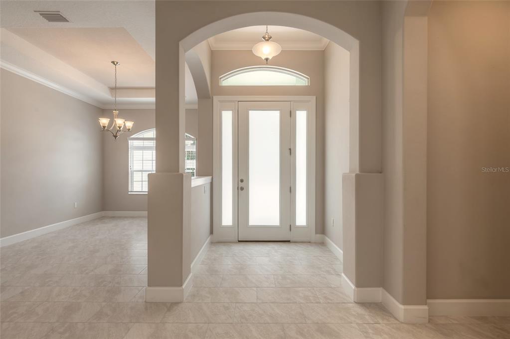 A tiled entryway features an arched opening, a white front door, and a dining area — 61 N RIVERWALK DRIVE, PALM COAST, FL