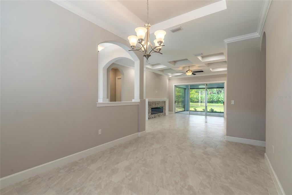 A dining area with a chandelier leads into a living room with a coffered ceiling — 61 N RIVERWALK DRIVE, PALM COAST, FL