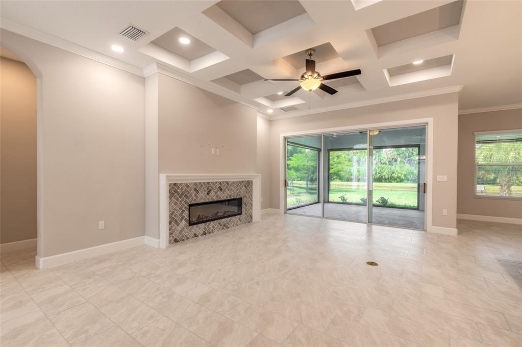 A living room features a coffered ceiling, a tiled fireplace, and sliding glass doors — 61 N RIVERWALK DRIVE, PALM COAST, FL