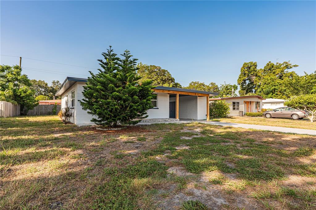 A single-story white house with a carport and a large evergreen tree in the yard — 1359 BARRY STREET, CLEARWATER, FL