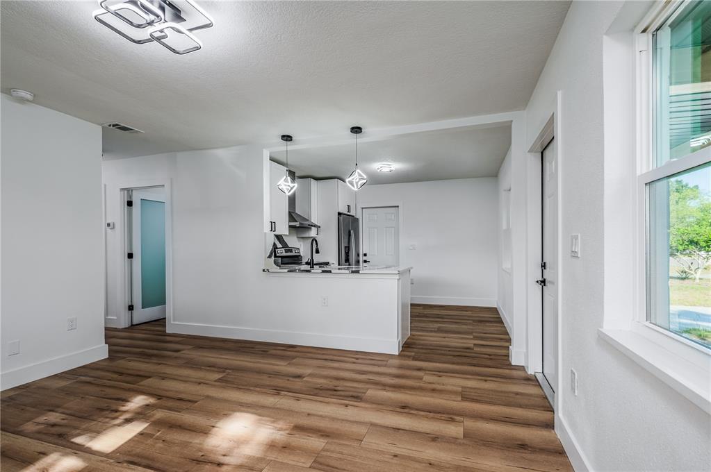 A kitchen with white cabinets and a breakfast bar overlooks an open living area — 1359 BARRY STREET, CLEARWATER, FL