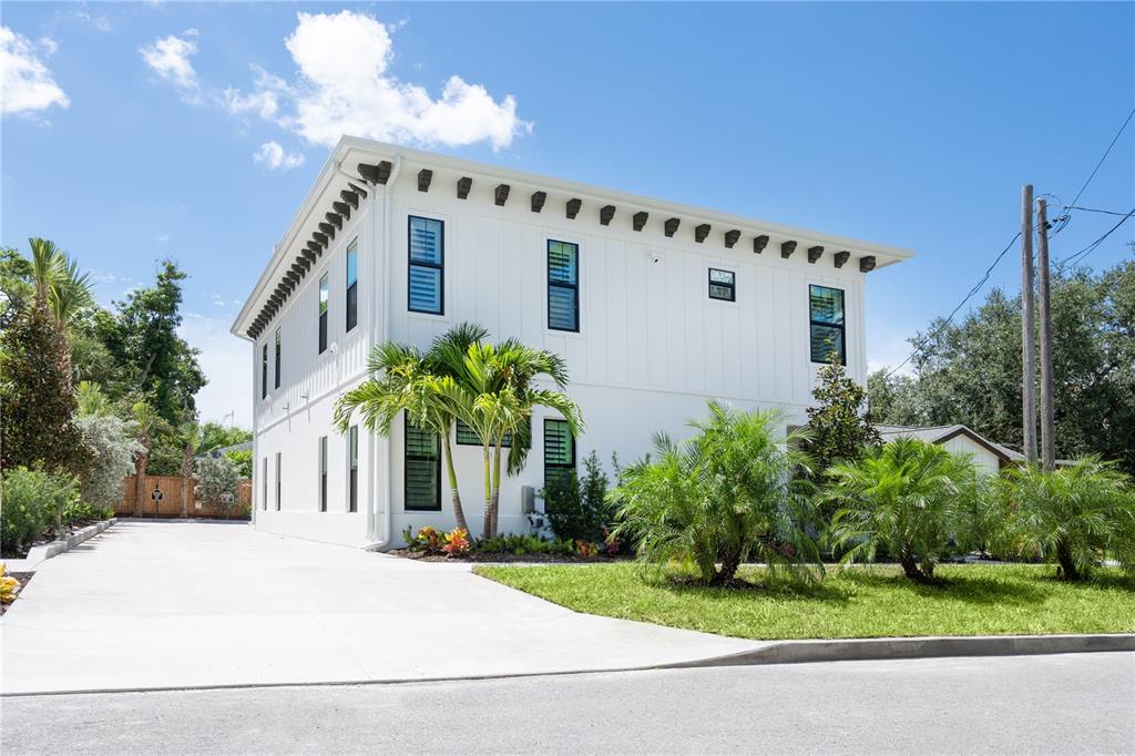 A two-story white house with dark window frames and a concrete driveway under a blue sky — 1234 15TH STREET UNIT 102, SARASOTA, FL