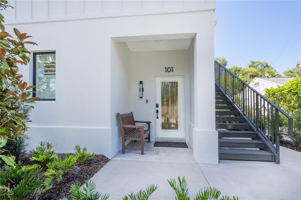 A white building exterior features a front door numbered 101, a wooden bench, and stairs — 1234 15TH STREET UNIT 102, SARASOTA, FL