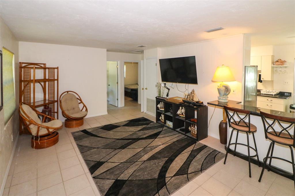 A living room with tile floors, a patterned area rug, wicker chairs, and a TV — 3580 SWANEE ROAD, PORT CHARLOTTE, FL
