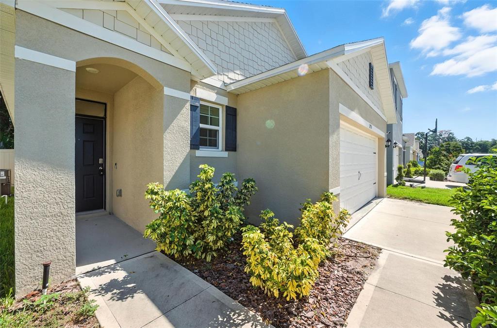 The exterior of a single-story house features a tan stucco facade, a garage, and landscaping — 1753 BENT BRANCH AVENUE, DELAND, FL