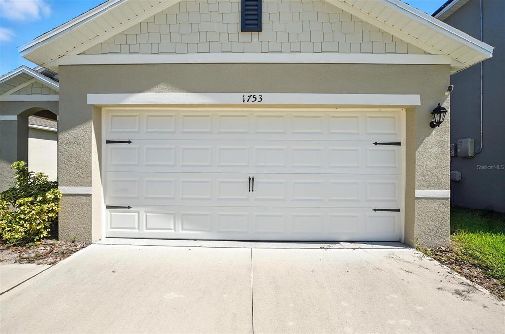 A white two-car garage door with decorative hardware on a tan house exterior — 1753 BENT BRANCH AVENUE, DELAND, FL