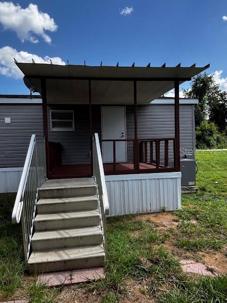 A mobile home features a covered front porch with stairs and metal railings — 15299 NE 238TH STREET, FORT MC COY, FL