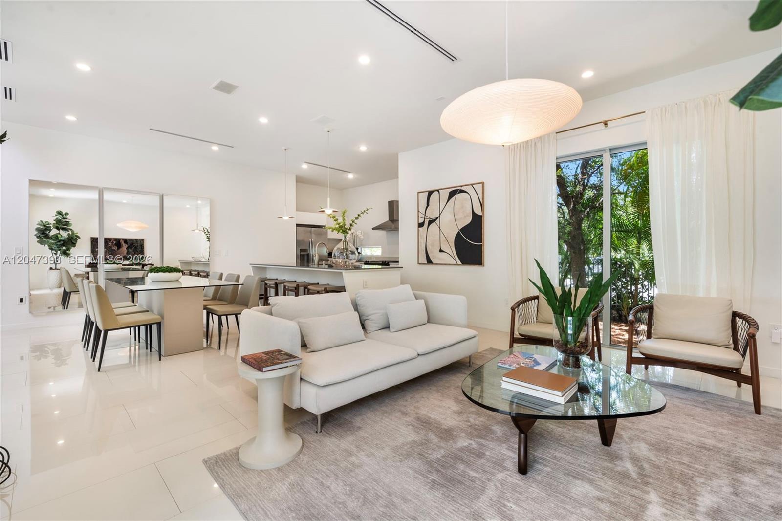 A modern open-concept living and dining area features white tile floors and a glass-topped table — 3253 Mcdonald St, Miami FL 33133, MIAMI, FL