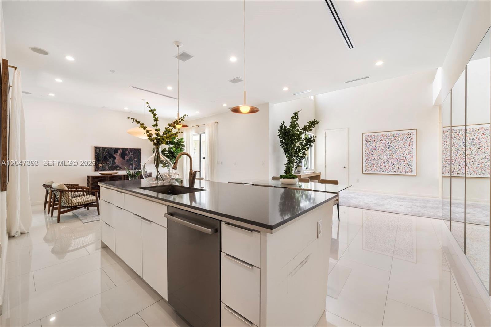 A modern kitchen features a large island with a dark countertop and white cabinetry — 3253 Mcdonald St, Miami FL 33133, MIAMI, FL