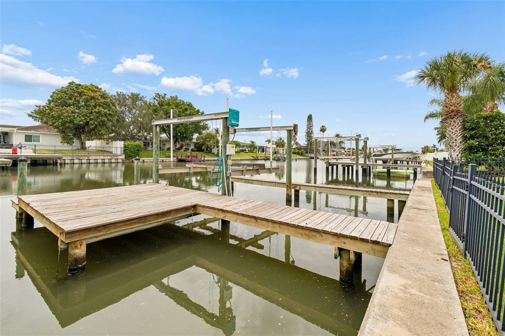 A wooden boat dock with a lift extends into a canal behind a residential property — 3941 E EDEN ROC CIRCLE, TAMPA, FL