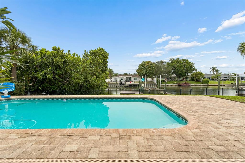 A swimming pool with a paver deck overlooks a canal with boat docks and houses — 3941 E EDEN ROC CIRCLE, TAMPA, FL