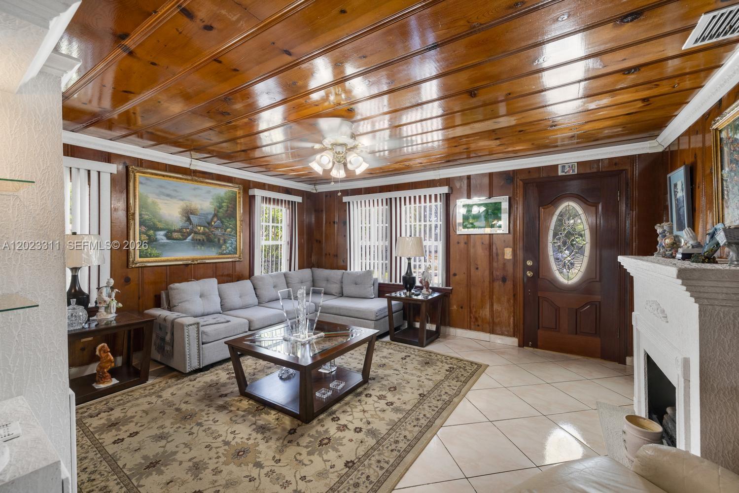 A living room features wood-paneled walls, a glossy wood ceiling, and a white fireplace — 2851 NW 106th St, Miami FL 33147, MIAMI, FL