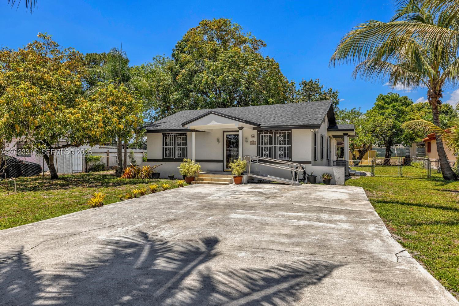 A single-story house with a concrete driveway, white exterior, and dark trim under a blue sky — 2851 NW 106th St, Miami FL 33147, MIAMI, FL