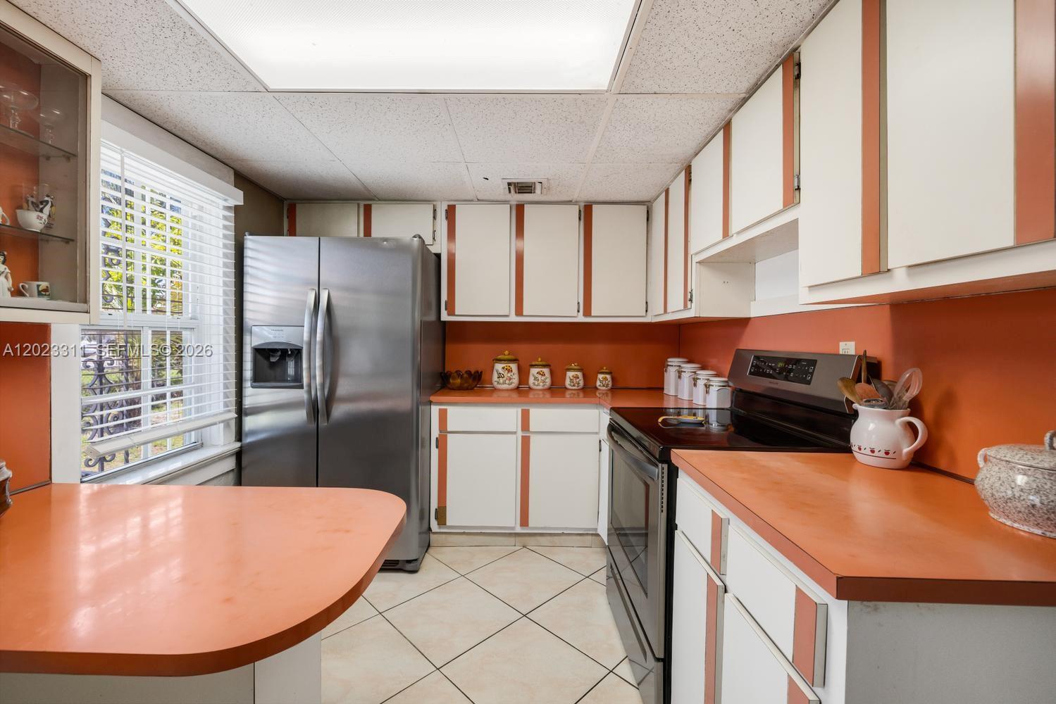 A kitchen features orange countertops, white cabinets with orange trim, and stainless steel appliances — 2851 NW 106th St, Miami FL 33147, MIAMI, FL