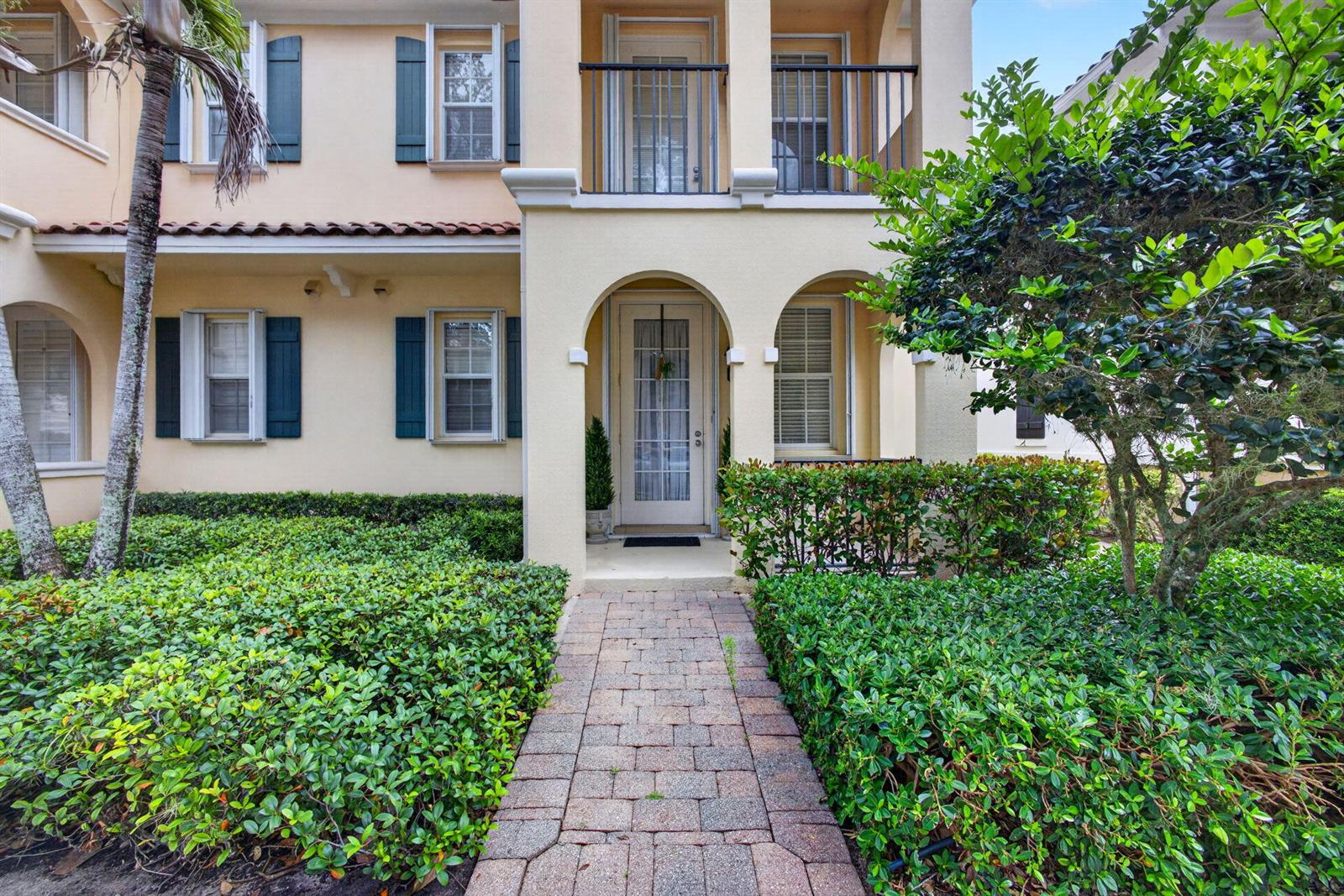 A paved walkway leads to the arched front entrance of a two-story stucco house — 213 Barcelona Drive, Jupiter FL 33458, JUPITER, FL