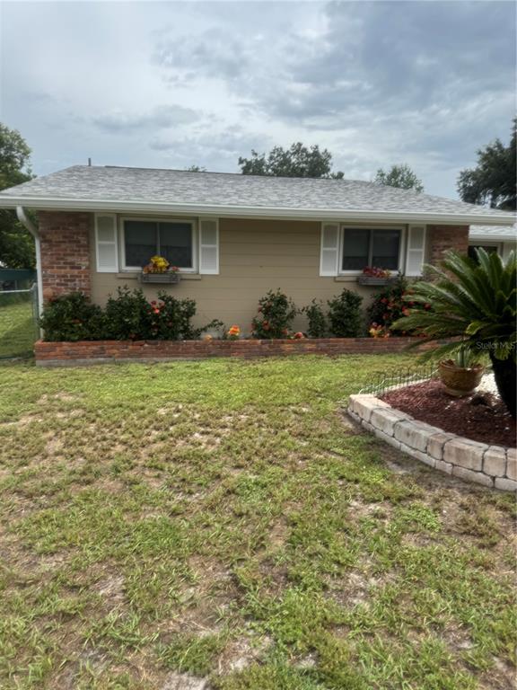 A single-story house exterior features tan siding, a brick accent wall, and a brick planter — 722 W WHIDDEN STREET, ARCADIA, FL