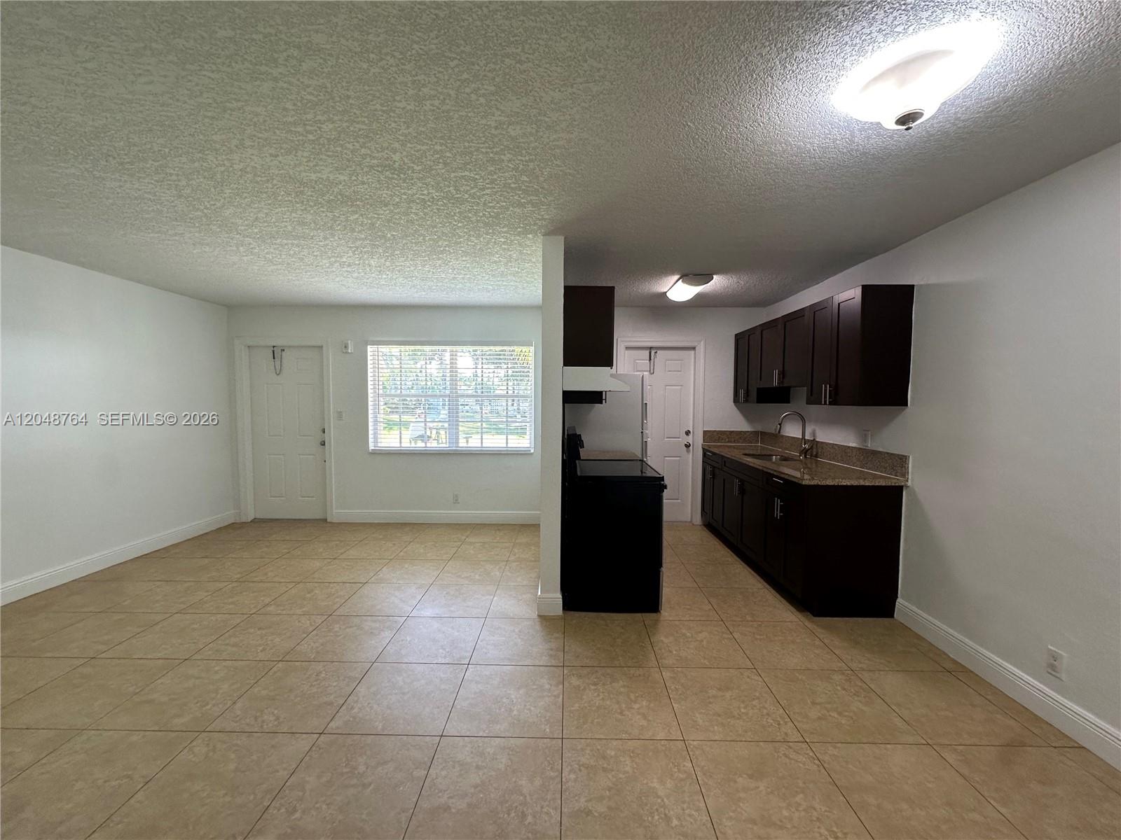 This room features a kitchen with dark cabinets and tile flooring adjacent to an entryway — 2900 NE 17th Ave # 109, Pompano Beach FL 33064, POMPANO BEACH, FL