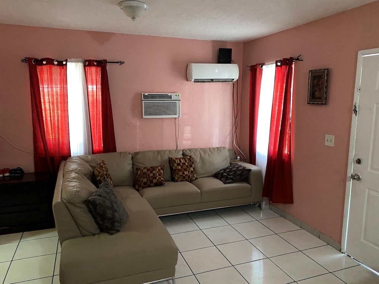 A living room features a beige sectional sofa, tiled floors, pink walls, and two air conditioners — 12920 Westview Drive # 1, Miami FL 33167, MIAMI, FL