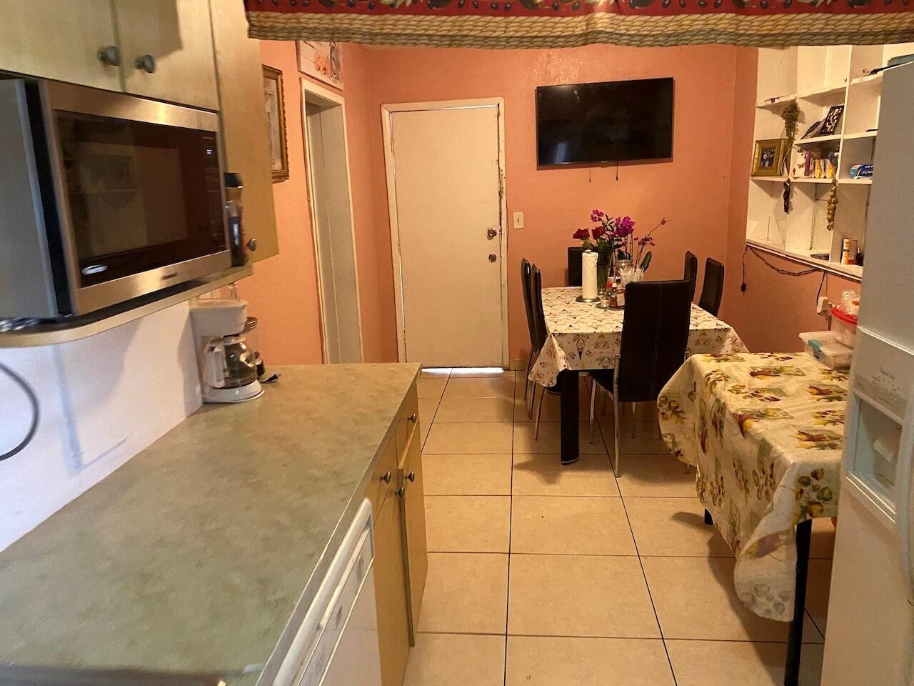 A kitchen with light countertops and a dining area with two tables and tiled floors — 12920 Westview Drive # 1, Miami FL 33167, MIAMI, FL