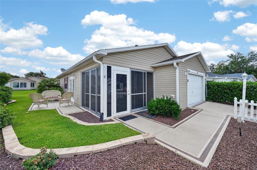 A tan house with a screened-in porch, a garage, and a landscaped front yard — 2673 SUFFOLK STREET, THE VILLAGES, FL