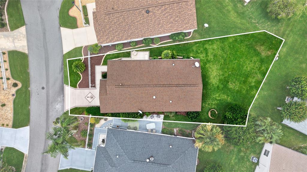 An aerial view shows a house with a brown roof and a large backyard lawn — 2673 SUFFOLK STREET, THE VILLAGES, FL