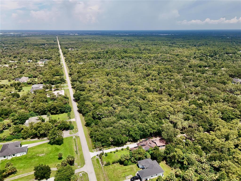 An aerial view shows a paved road running through a wooded residential area — 35TH AVENUE NW, NAPLES, FL