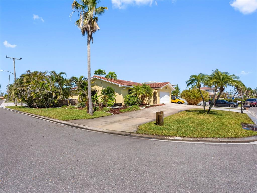 A single-story yellow house with a tile roof and driveway sits on a corner lot — 562 JOHNS PASS AVENUE, MADEIRA BEACH, FL