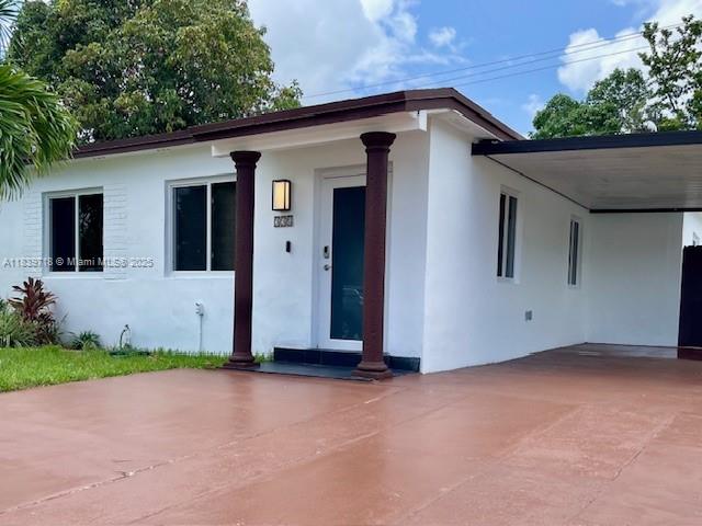 A white single-story house features a brown-trimmed roof, two dark columns, and a side carport — 330 W 40th Pl, Hialeah FL 33012, HIALEAH, FL